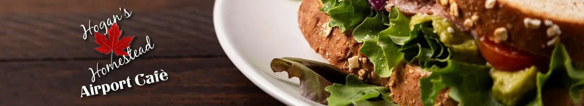 Close up of sandwich on a white plate that sits on a wooden table
